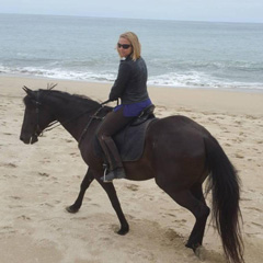Natalie D'Onofrio riding a horse on the beach'